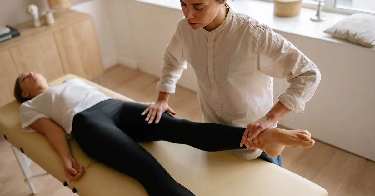 A chiropractor performing a lower-body adjustment on a patient lying on a treatment table.
