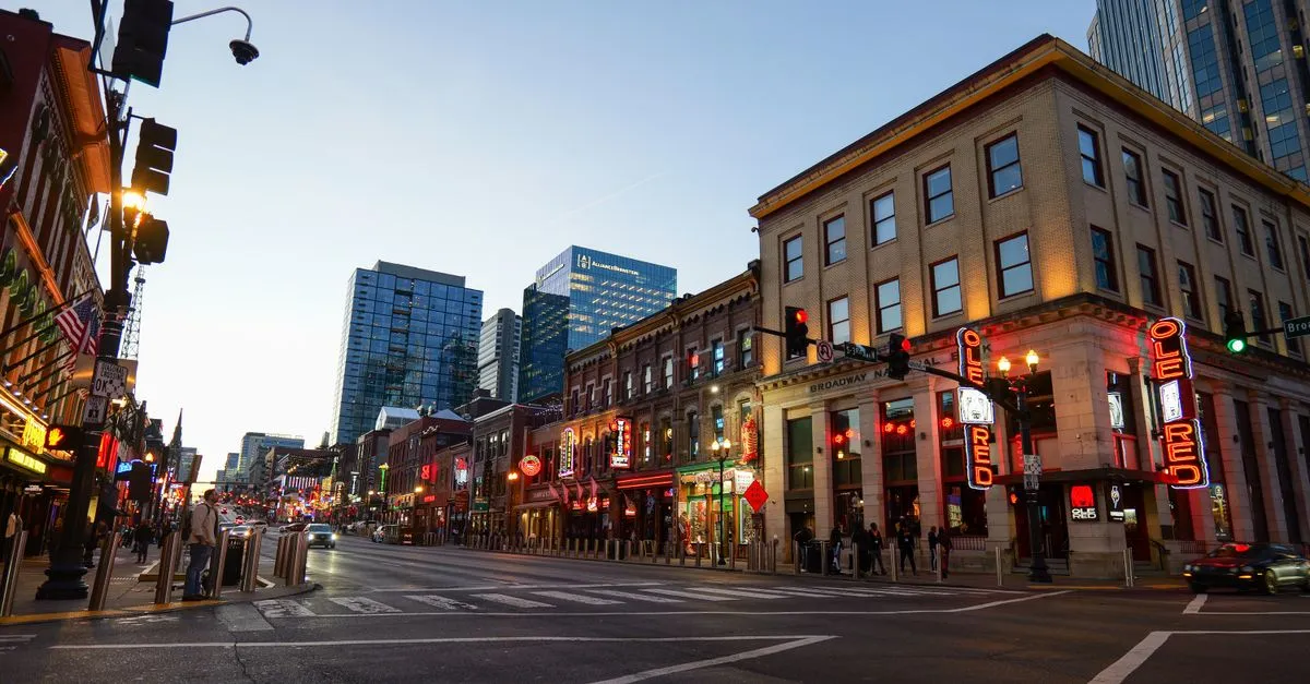 A Broadway street corner in downtown Nashville with brick storefronts, neon bar signs, and Gulch high-rises rising behind, the kind of local market local SEO is built for.