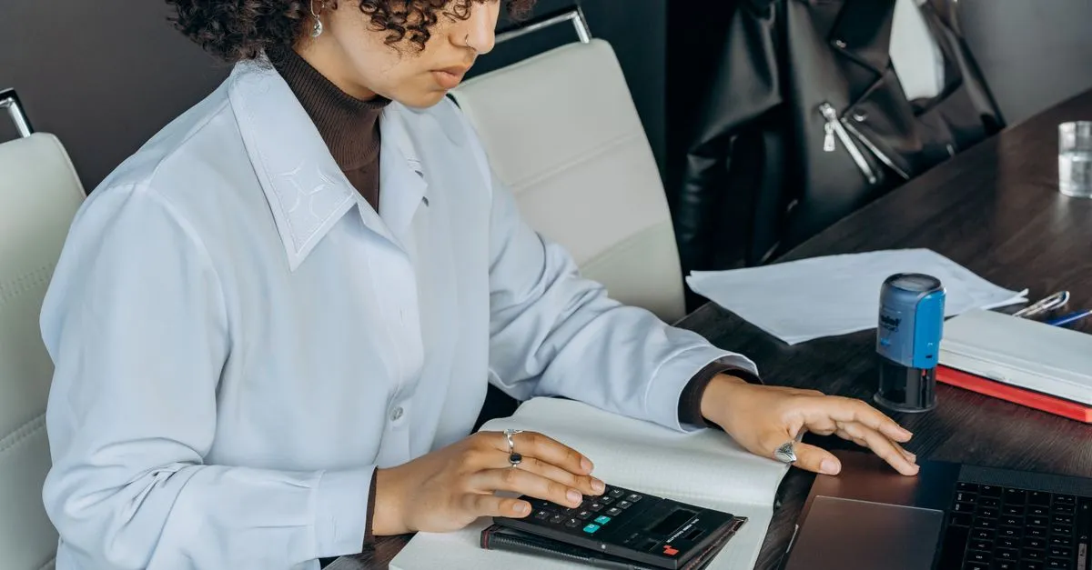 An accountant using a calculator to work through figures at a desk, the kind of local firm that wins tax preparation near me searches.