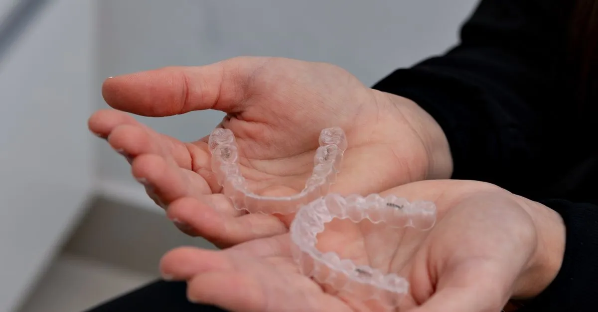 Hands holding clear dental aligners in an orthodontic office, the clear-aligner treatment an orthodontist SEO page helps patients research before they book.