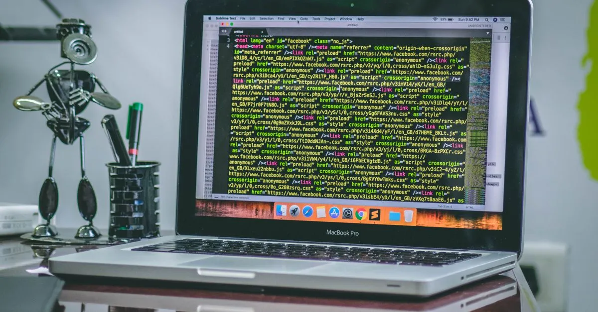 A MacBook Pro on a desk displaying lines of website code, a clean workspace for building a site in real code.