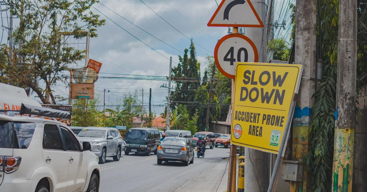 A busy accident-prone city street with a slow down warning sign, cars, and a motorcycle, the kind of crash that starts an injury case.