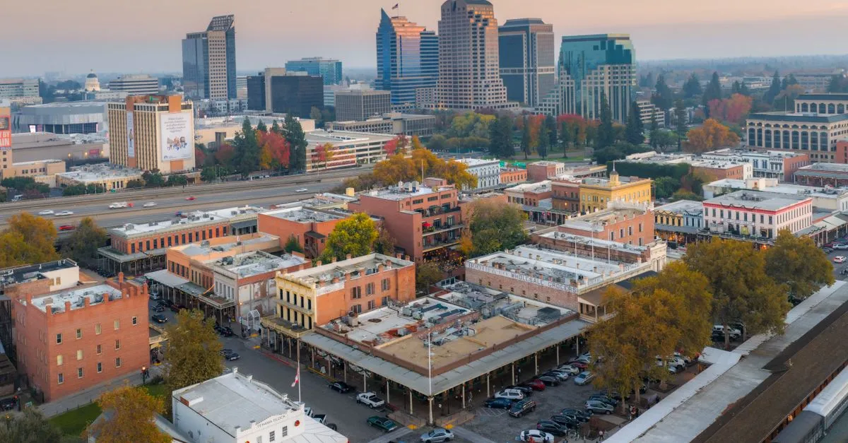 Historic brick storefronts in Old Sacramento with the downtown skyline and a glimpse of the Capitol dome behind them, the kind of local market local SEO is built for.