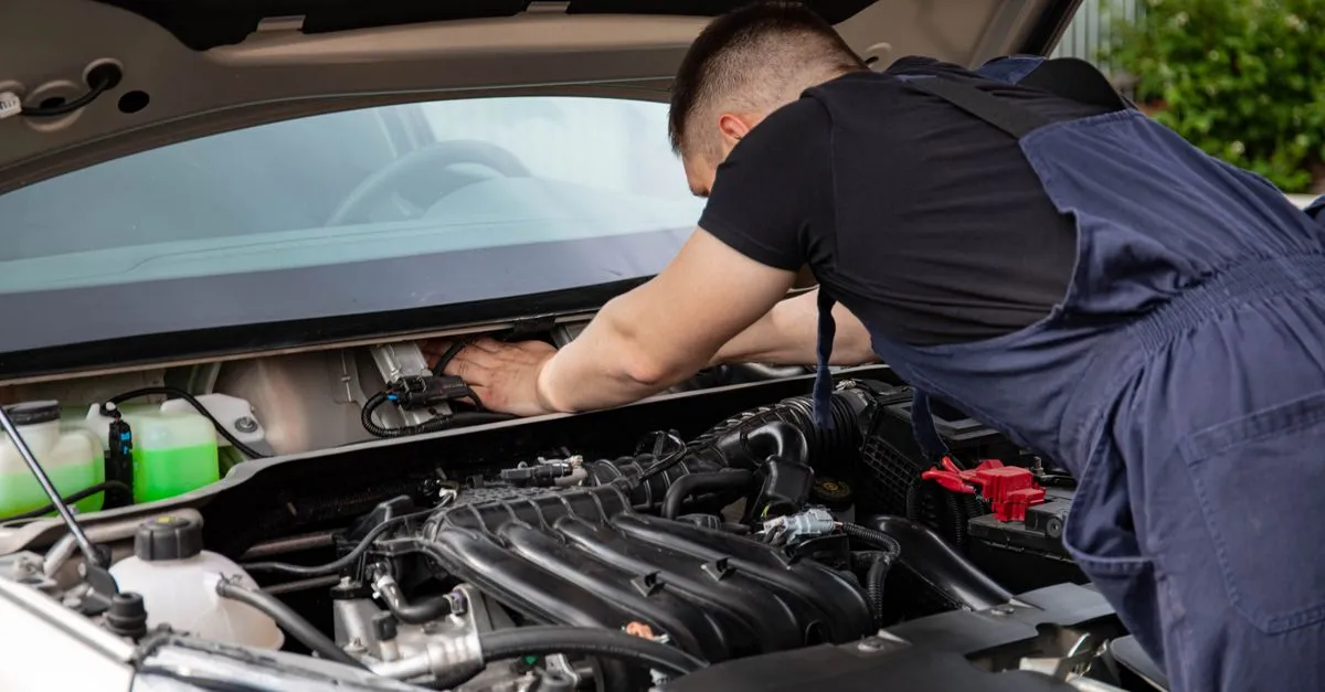A mechanic in a repair shop working on a car engine, the kind of service automotive SEO gets found for.
