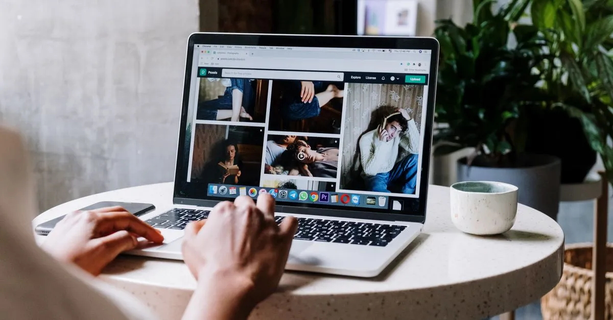 A web designer working on a responsive website layout on a laptop at a table.