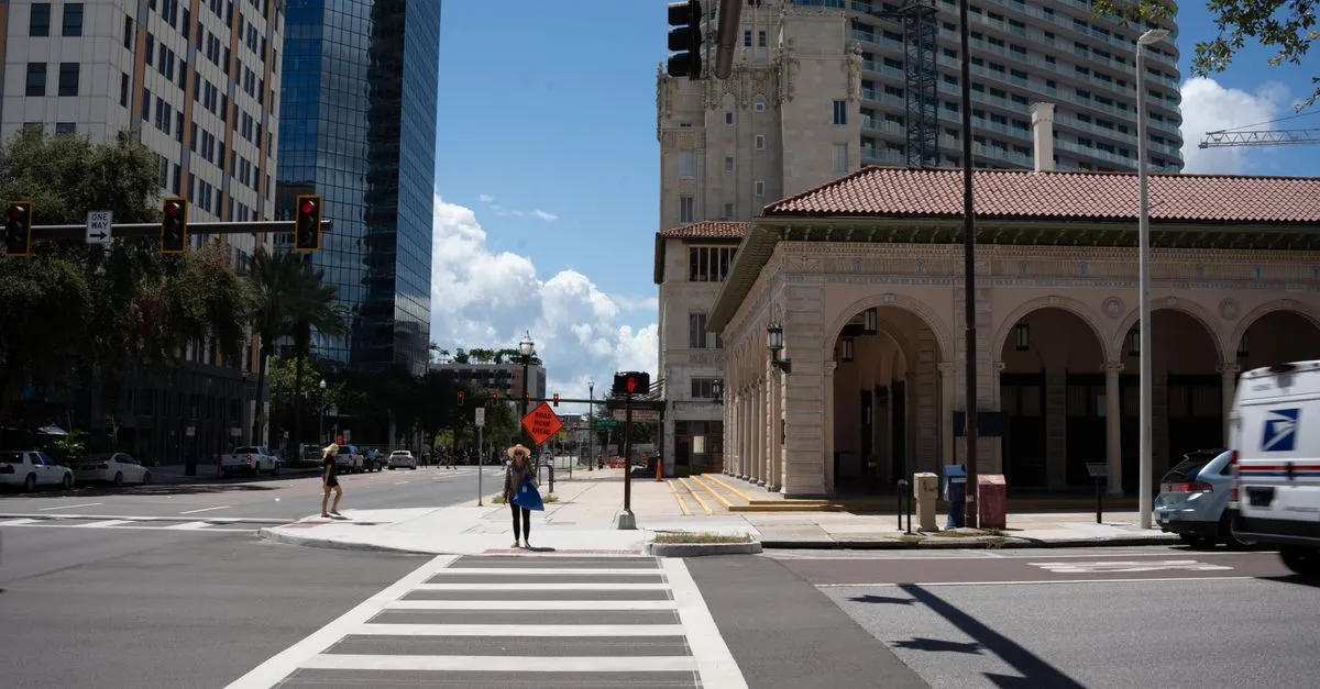A downtown Tampa intersection where a historic Mediterranean-revival building stands beside modern high-rises, the old and new competing for the same block.