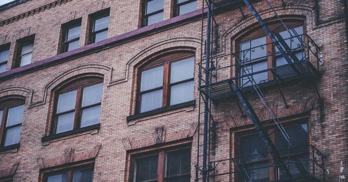 A historic multi-story brick building with arched windows and iron fire escapes, echoing the warehouse architecture of Old Town Wichita.