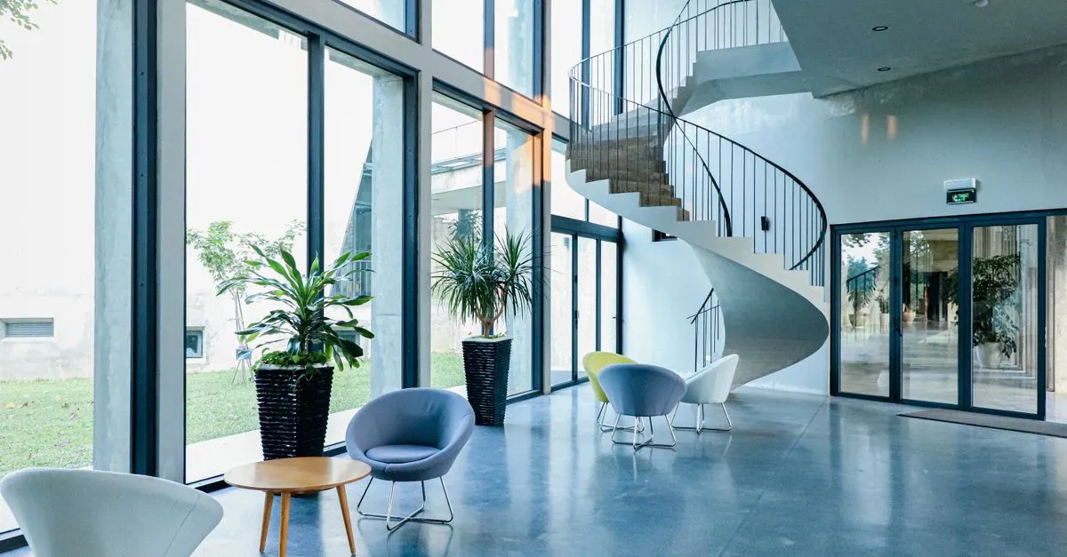 The bright multi-story lobby of a large corporate office building with a spiral staircase.