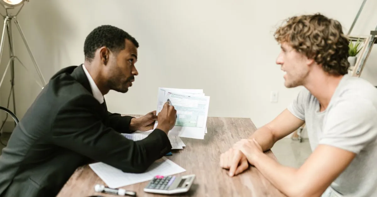 An accountant reviewing tax paperwork with a client at a desk in a modern office.