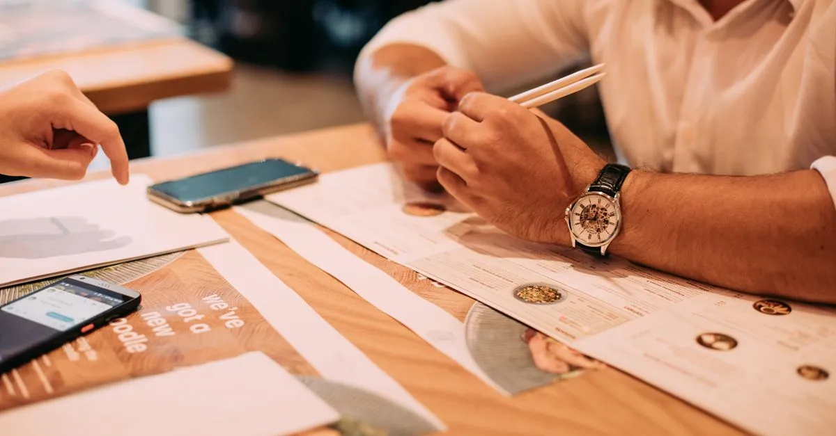 Diners looking over printed menus with phones on the table, the moment a restaurant website is built to win online.