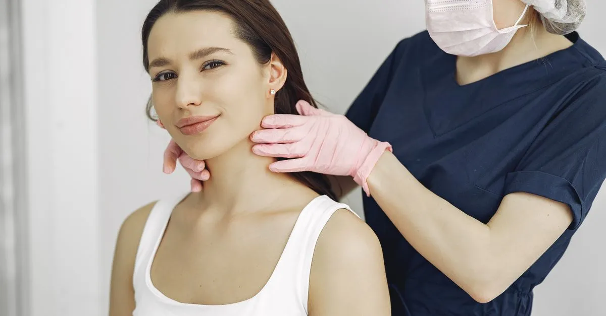A dermatology clinician examining a patient's skin during an exam in a modern clinic.