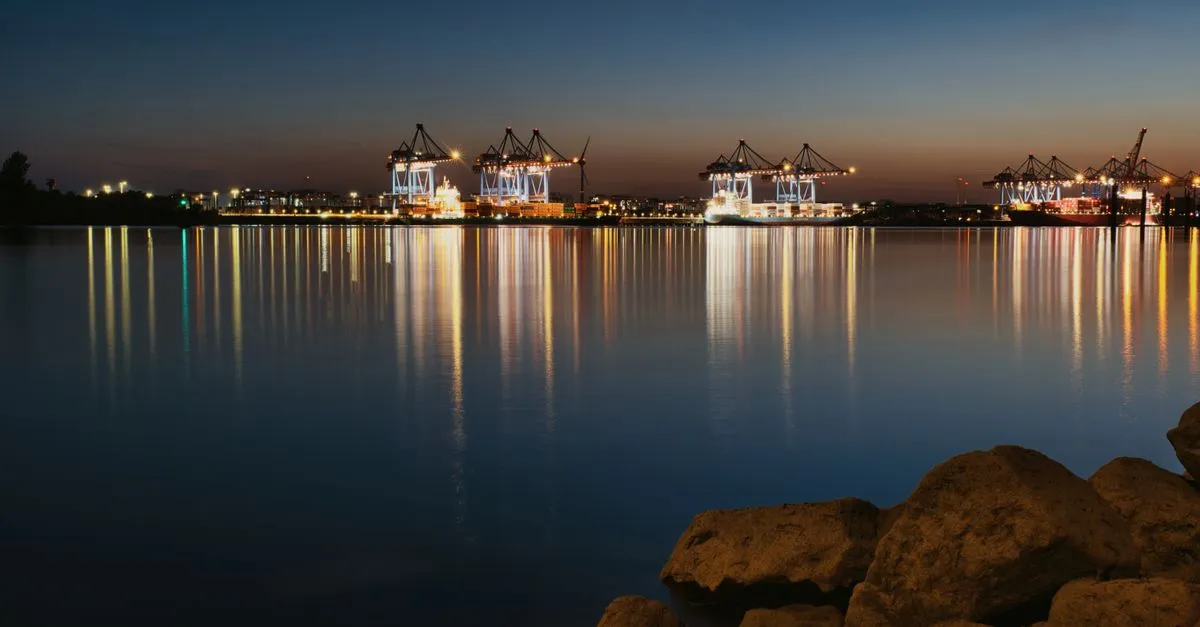 A container port at dusk with illuminated cranes reflecting on the water, the kind of logistics hub Jacksonville is known for.
