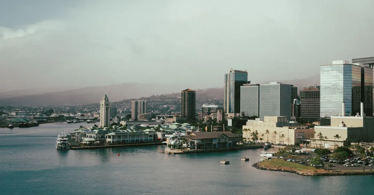 The downtown Honolulu waterfront at dusk, with Aloha Tower and office buildings rising behind Honolulu Harbor.