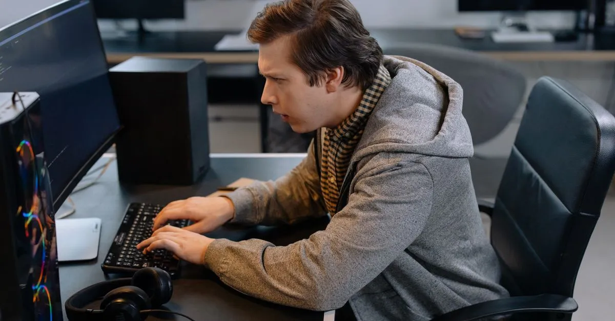 A focused programmer working at an office desk, typing code on a keyboard.