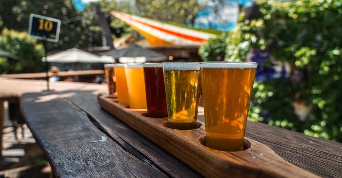 A craft beer flight on a wooden paddle at a sunny San Diego taproom, the kind of local business the map pack decides.