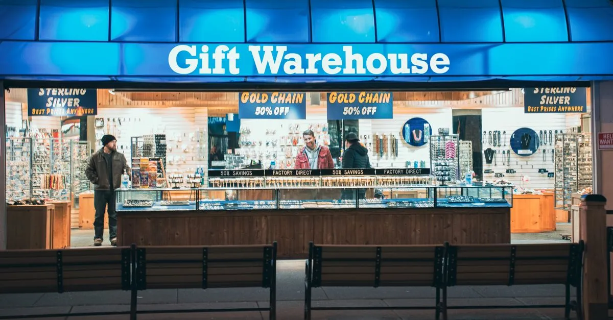A chain store storefront at night with bright blue exterior signage and customers inside.