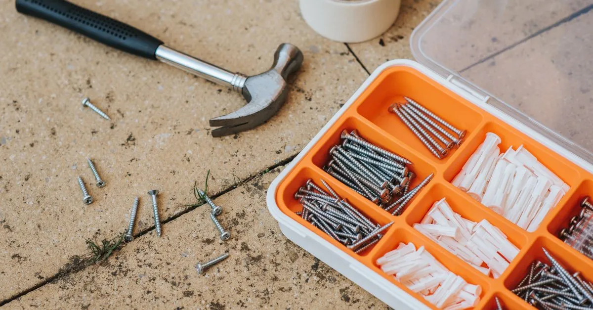 A box of assorted home repair tools and screws next to a hammer, the everyday kit of a home-services trade that homeowners search for by the job.