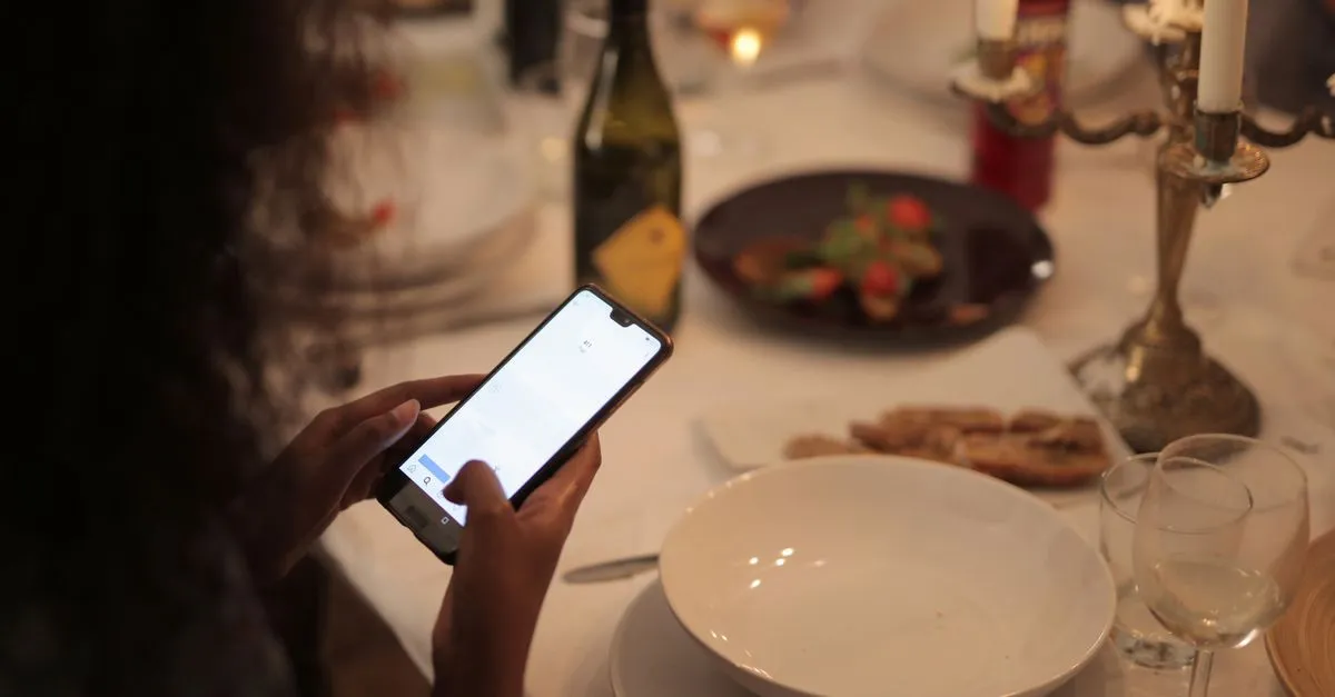 A person using a smartphone at a restaurant table, the way most diners find a place to eat.