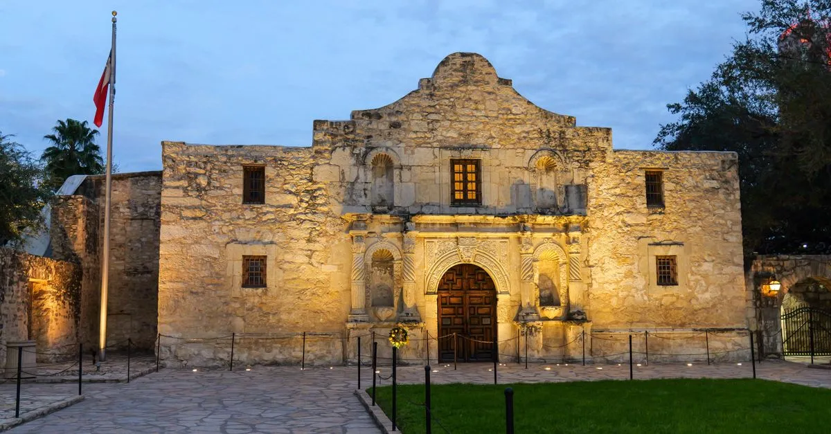 The historic Alamo lit at dusk in downtown San Antonio, a symbol of the tourism the local economy runs on.