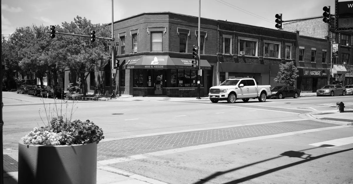 A busy Chicago neighborhood intersection lined with historic brick storefronts and local businesses.