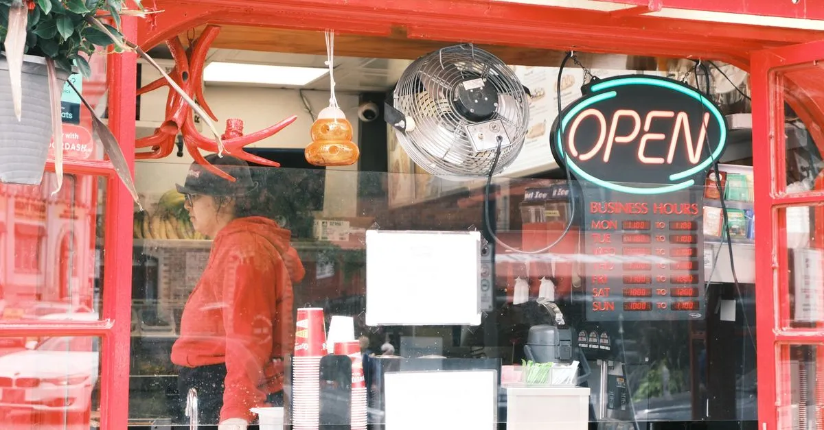 A small neighborhood cafe storefront with a neon open sign and posted business hours, the kind of Seattle local business that lives or dies by the map pack.