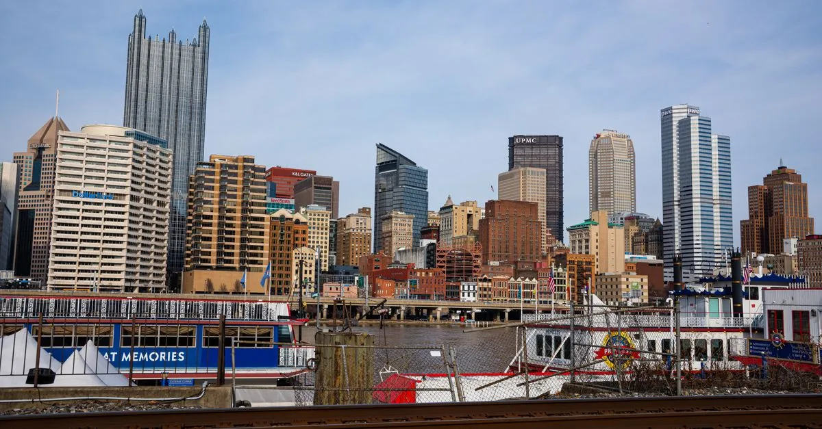 The downtown Pittsburgh skyline with the gothic spires of PPG Place and riverboats docked along the waterfront under a pale winter sky.