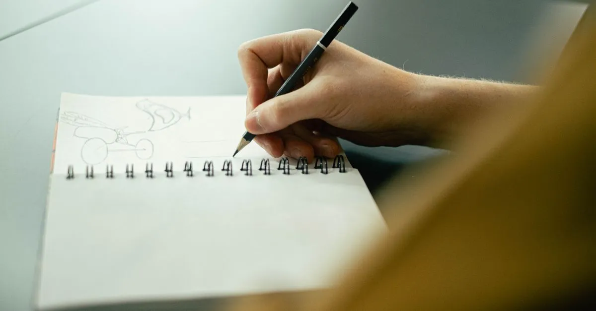 A hand sketching ideas in a spiral notebook with a pencil, the planning that goes into a Cleveland site build.