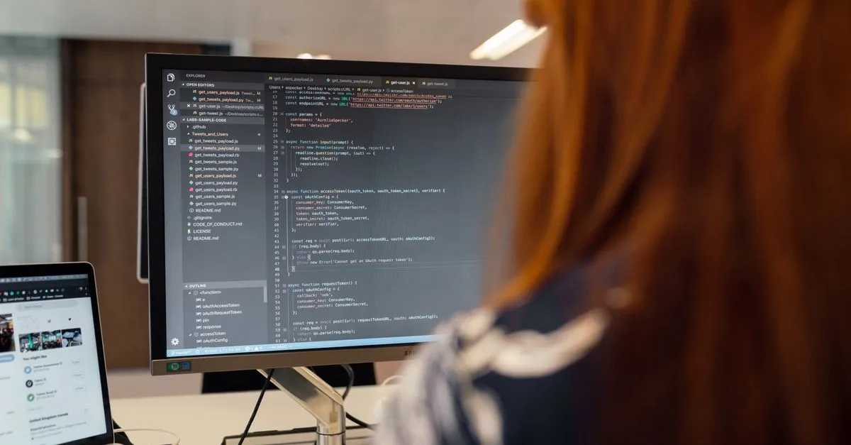 A software developer writing code in an editor on a large monitor while building a website.