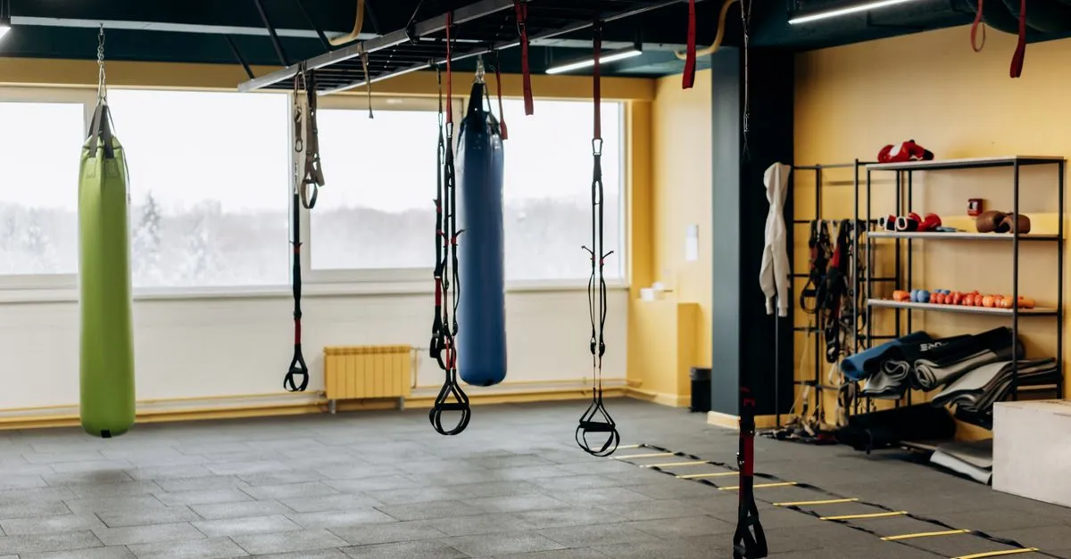 A spacious modern gym interior with weights, punching bags, and open floor space.