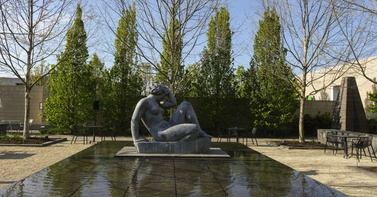 A reclining figure sculpture set in the reflecting pool of the Columbus Museum of Art sculpture garden.