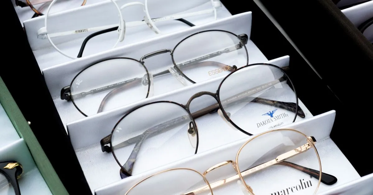 Rows of prescription eyeglass frames displayed on a shelf in an optometrist's optical shop.