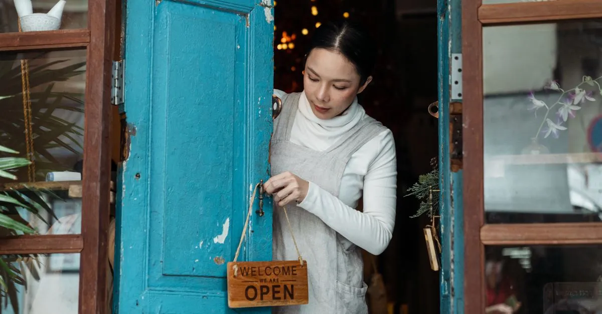 A franchise owner hangs the open sign at their local storefront, one location of a larger brand.