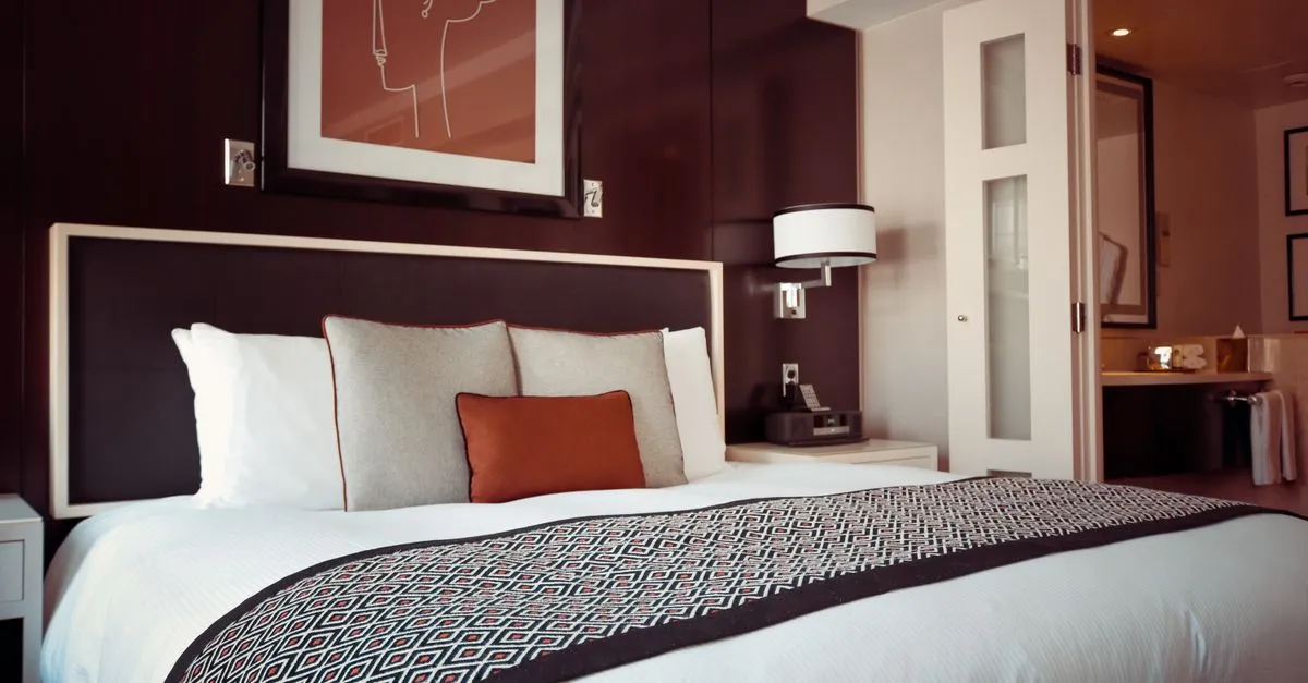 A made bed in a clean, modern hotel guest room, the kind of room travelers book after finding a hotel in search.