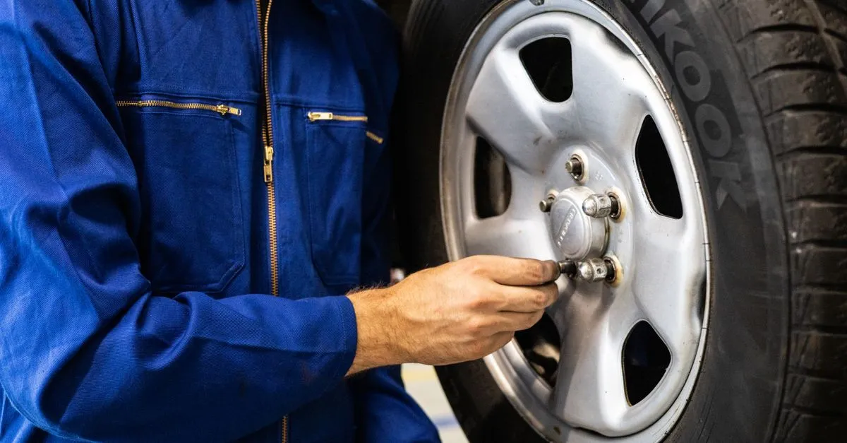 A tire technician in blue coveralls inspecting a car tire in a repair shop, the kind of local tire shop that wins tires near me searches.