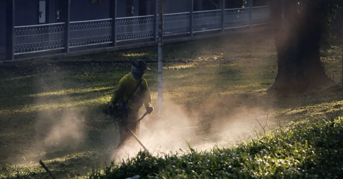A landscaper mowing green grass in bright sunlight, the recurring maintenance work organic SEO helps a landscaping company book.