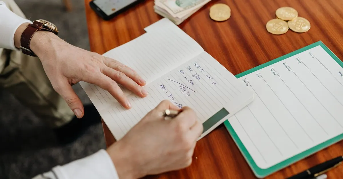 Writing a budget in a notebook, planning marketing spend around a percentage of revenue.