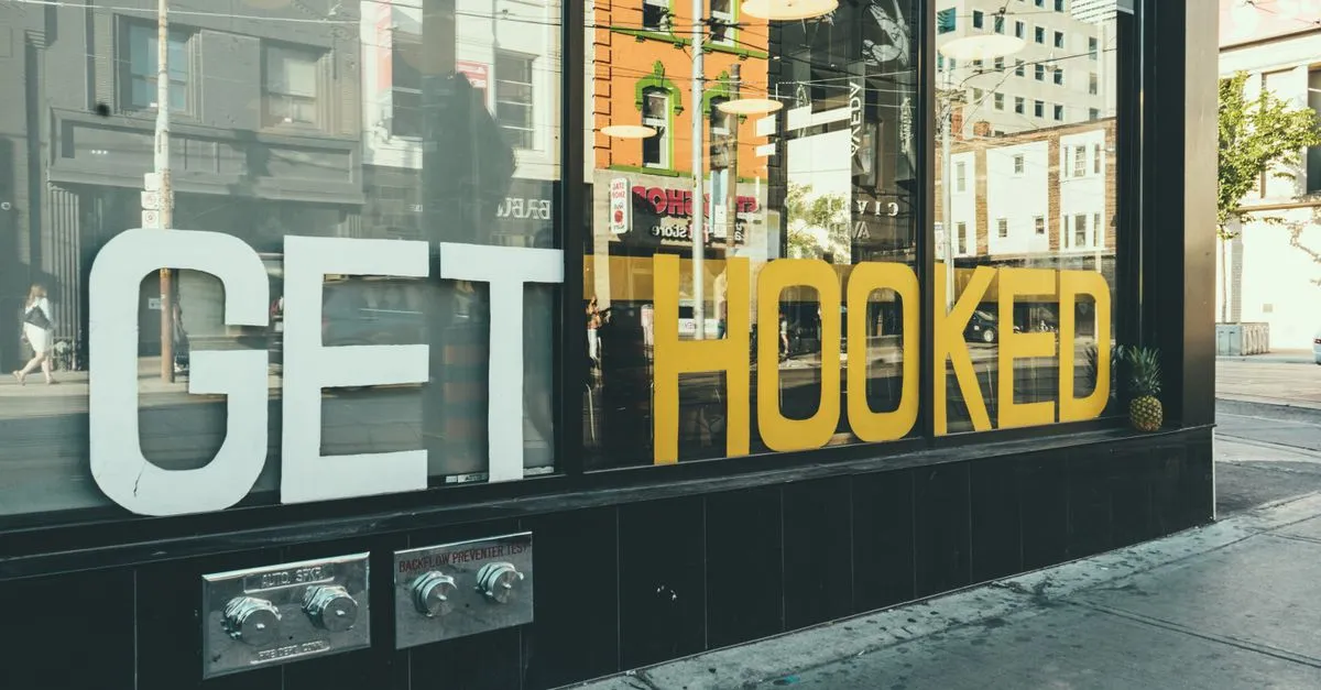 Street scene reflected in a glass storefront with a large 'Get Hooked' sign, an example of clear above-the-fold messaging.