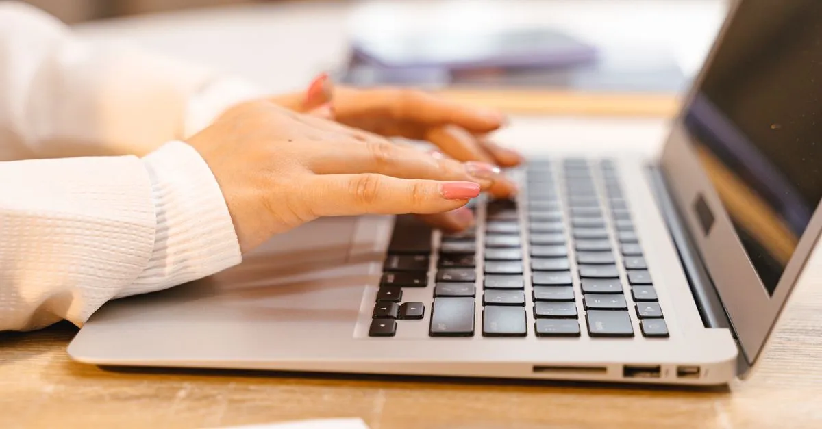 Hands typing on a laptop, creating content structured for AI engines.
