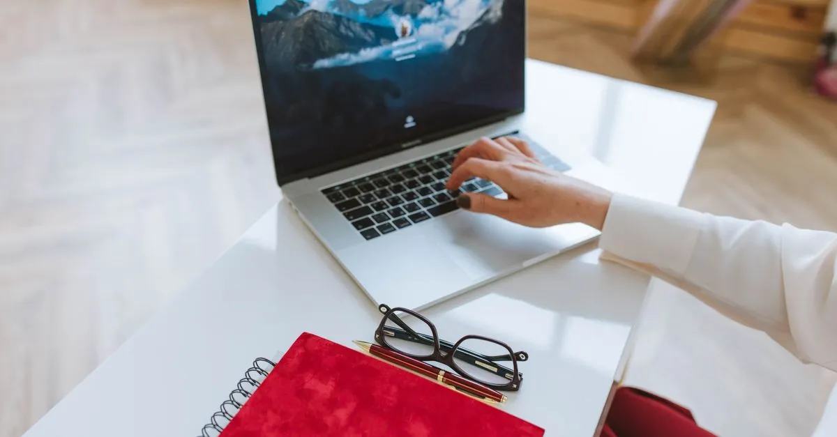 A person typing business details into a laptop at a desk, the routine work of keeping directory listings accurate and consistent.