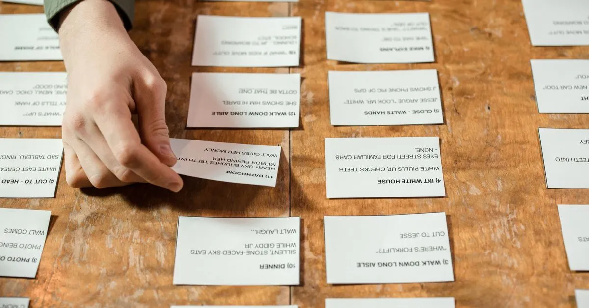 A person sorting printed cards with text into groups on a wooden table.