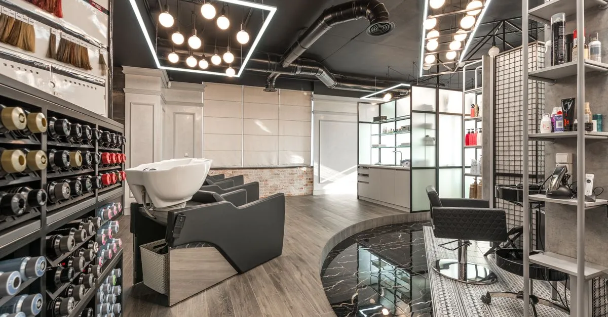 A modern beauty salon interior with a backwash chair, styling station, and product shelves, the kind of room a salon website is built to match.
