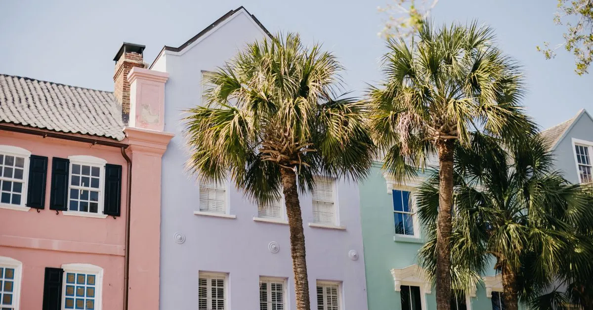 Colorful pastel row houses and palmetto palm trees on a sunny street in Charleston, South Carolina.