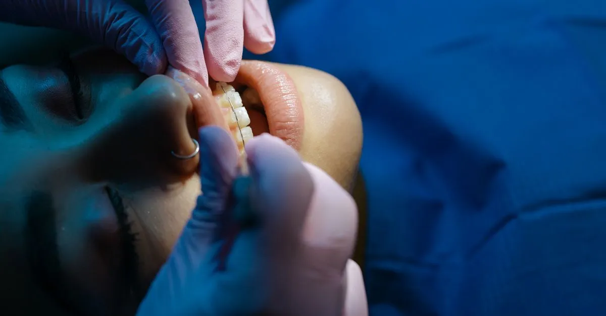 An orthodontist in gloves adjusting a patient's braces during a checkup, the kind of practice local SEO for orthodontists helps families find.