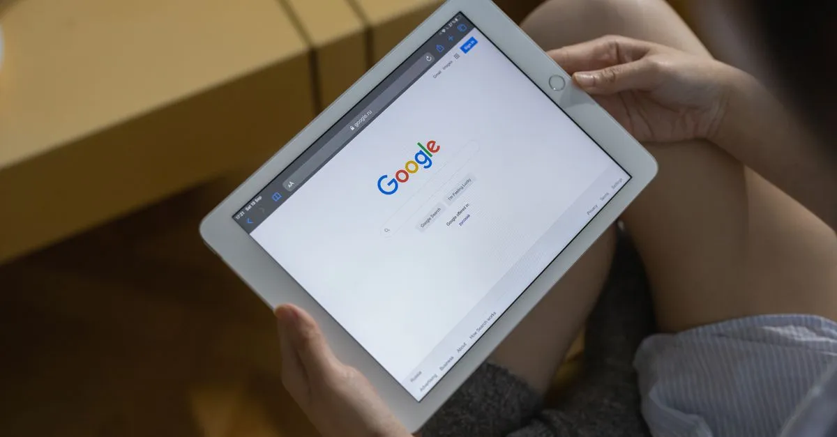 Hands holding a tablet showing Google’s search homepage in a browser, where meta titles appear in results.