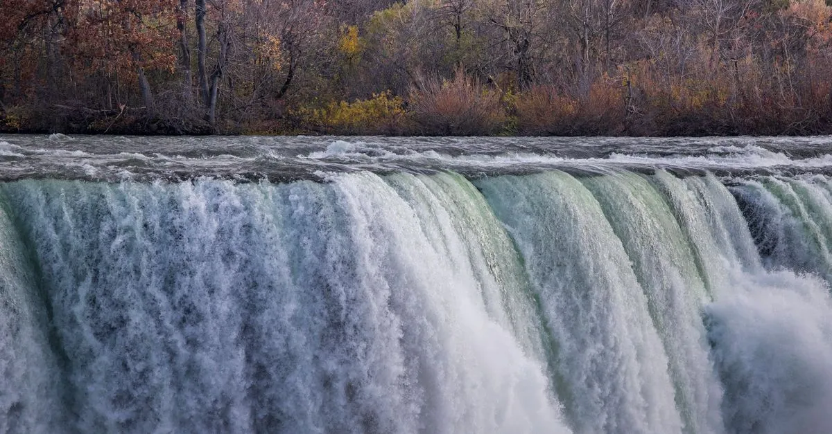 The American Falls at Niagara, in the Buffalo Niagara region of Western New York, framed by autumn foliage along the far shore.
