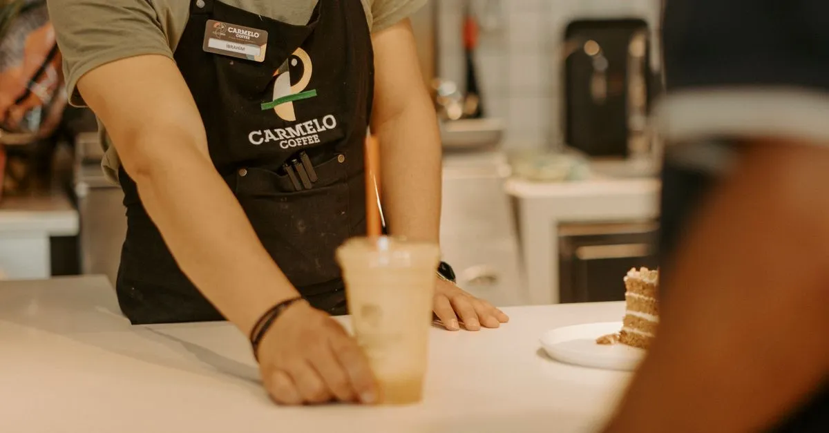 A barista handing an iced coffee across the counter, the kind of local business that shows up in Google Business Profile searches.