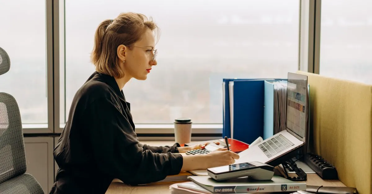 An accountant working with a laptop and calculator at a desk, the kind of local firm clients find when they search for a cpa near me.