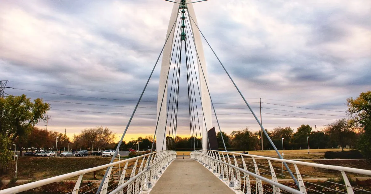 A cable-stayed pedestrian bridge over the Arkansas River at sunset in Wichita, Kansas.
