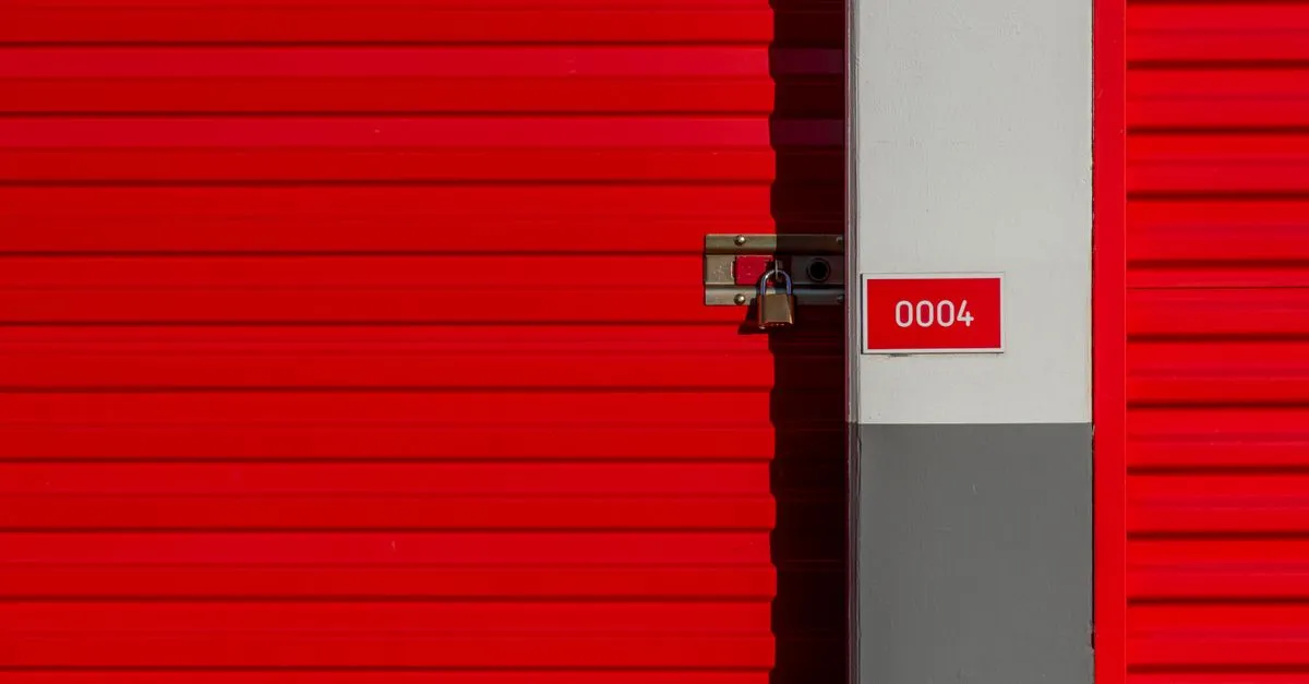 Padlocked red self storage unit door numbered 0004 along a facility hallway.