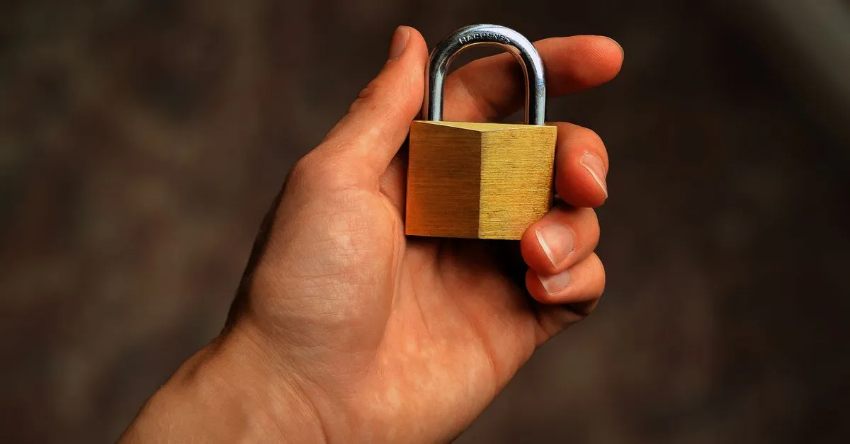 Hand holding a brass padlock, standing in for HTTPS website security and encryption